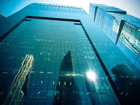 Bottom view of modern office building with reflection of skyscrapers on glass Stock Photos