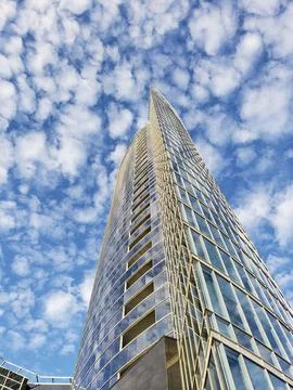 Bottom up view of a modern office building against a blue sky with white clou Stock Photos