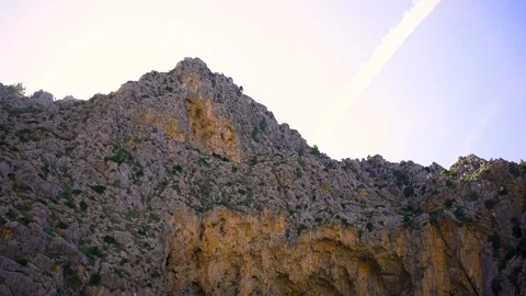Bottom view of a mountain slope on blue sky background with a white plane trace Vidéo 119769321