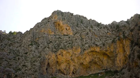 Bottom view of a mountain slope on bright sky background. Art. High cliff with Vidéo 119769679