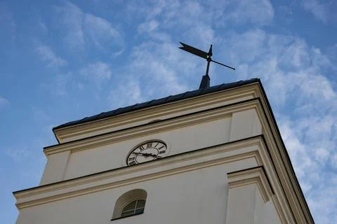 Bottom view of an old stone clock tower with a weather vane against the blue  Stock Photos