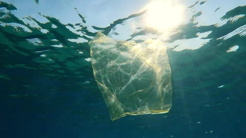 Bottom view of old yellow plastic bag drifting below water reflected on surface Stock Footage 327560378