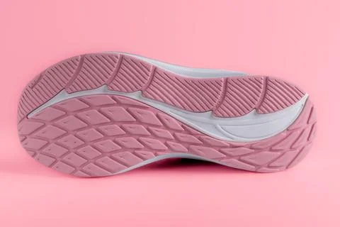 Bottom view of pink running sneaker sole with tread pattern on pink backgroun Stock Photos