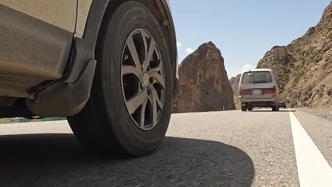 Bottom view of the right-front wheel of an SUV and a minivan moving in front Stock-Footage 241381623