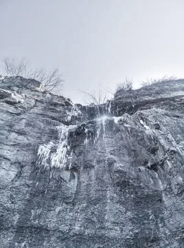 Bottom-up view of a rock with a small waterfall formed by a stream. Stock Photos