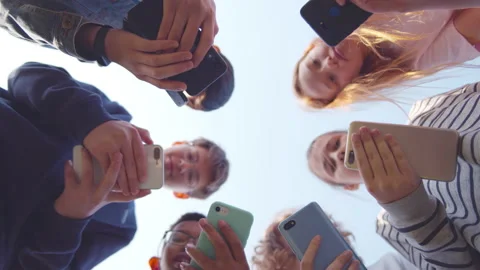 Bottom view of school children use smartphone outdoors. Realtime Stock Footage 233888591
