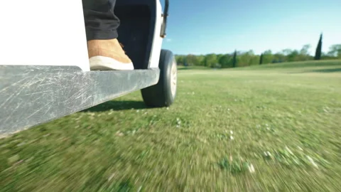 Bottom view shot of driving golf cart along the mowed green lawn with feet of Stock Footage 268599330