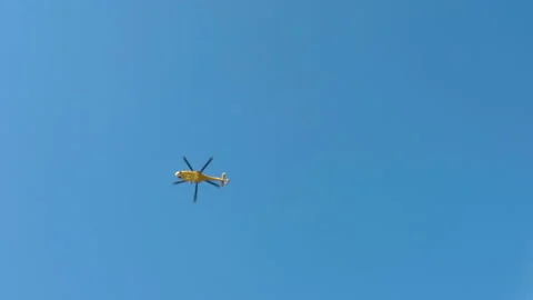 Bottom view shot of flying yellow helicopter against clear blue sky background Video stock 228721846