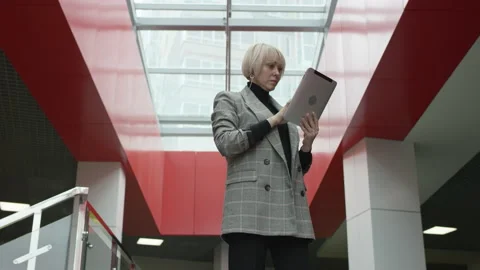 A bottom view slow motion close up shot of a blonde business woman in a grey Stock Footage 139312133