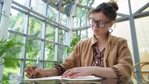 Bottom view. smart serious joung brown hair student in brown cloak writes in Stock Footage 147404753