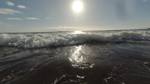 A bottom-up view of the surf on an Atlantic Ocean beach under a blue sky. Video stock 328371699
