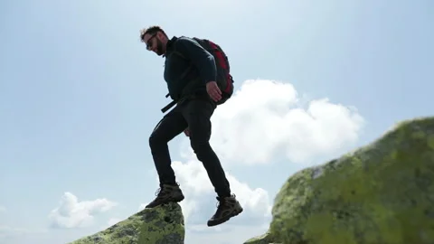 Bottom view of a tourist-climber walking along the rocky mountains. Stock Footage 247663700
