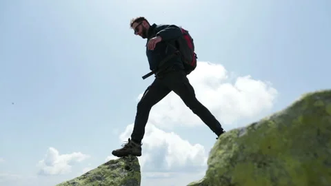 Bottom view of a tourist-climber walking along the rocky mountains. Stock Footage 247663707