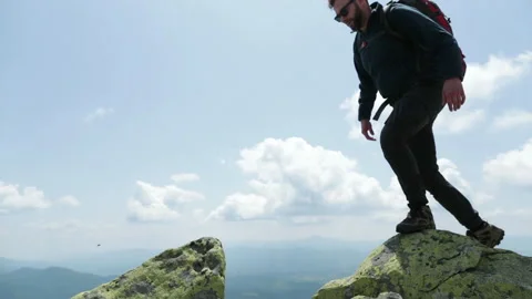 Bottom view of a tourist-climber walking along the rocky mountains. Stock Footage 247663718