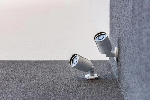 Bottom view of two security cameras on office building, security system conce Stock Photos