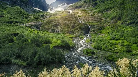 A bottom view of a waterfall flowing from a glacier in a mountain gorge. Moun Stock Photos