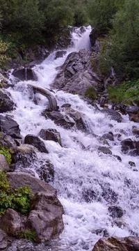 A bottom view of a waterfall flowing from a glacier in a mountain gorge. Moun Stock Photos