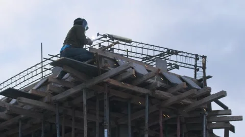 Bottom view of a welder working on the roof of a building under constructio 스톡 동영상 273815323