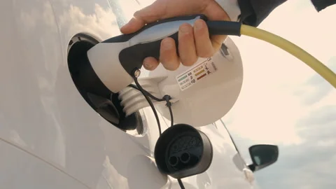 Bottom view of woman hand inserts power cable supply to charge electric or EV Видео 156709818