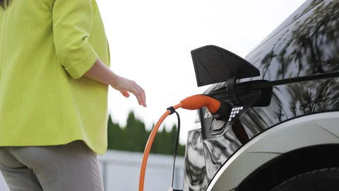Bottom view of woman hand inserts power cable supply to charge electric or EV Stock Footage 271628410