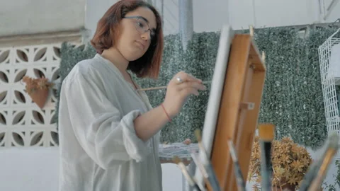 Bottom view of young painter with brush and artist easel on patio Stock Footage 130617604