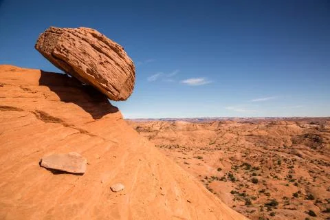 Boulder balanced on edge over sandstone cliff Stock Photos