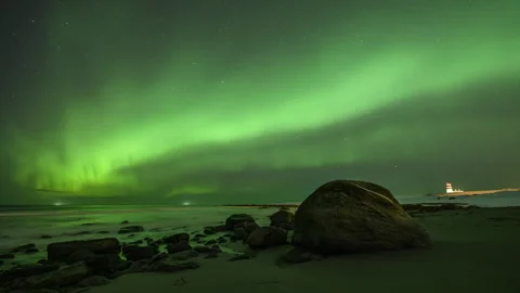 Boulder on the coast with a lighthouse and Aurora Borealis Stock Footage 251341926