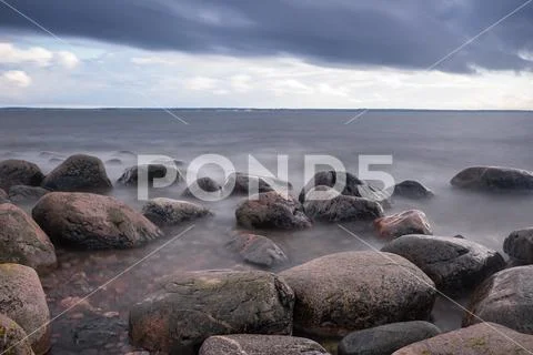 Boulders, forest, shore, evening light, sunset, clouds, blue sky and rainbow Stock-Fotos