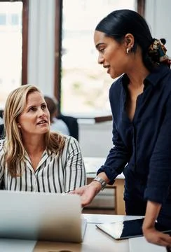 Bouncing ideas off of one another. an attractive businesswoman helping a female Stock Photos