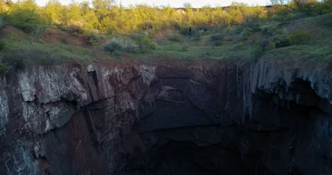 Bouncing slackline with a man walking on it, over a huge hole in the ground, 4k Stock Footage 133556691