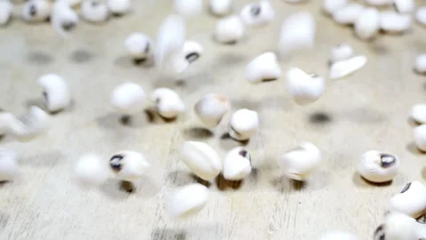 Bouncing white beans with black eyes on a wooden surface Stock Footage 292302673