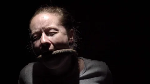 Bound hostage sits in dark room under beam of light. Stock Footage 102541787