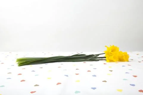 A bouquet of daffodils placed on a tablecloth patterned with multiple color.. 스톡 사진