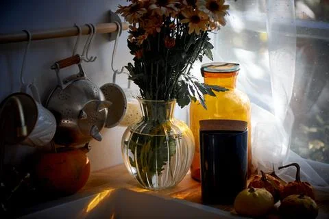 A bouquet of daisies stands in the kitchen near the sink. light from a large Stock Photos