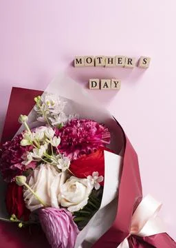 A bouquet of flowers and a block of text for mother placed on a pink backgrou Stock Photos