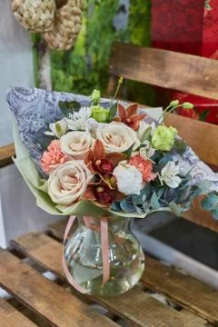 A bouquet of flowers in a glass vase on a background of wooden boards in a wa Stock Photos