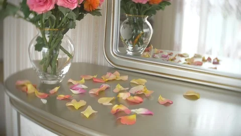 Bouquet of multi-colored roses in a transparent round glass vase is on the table Vidéo 89628913