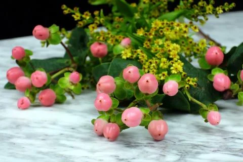 Bouquet of pink and yellow flowers lying on a marble table with a black backg Stock Photos