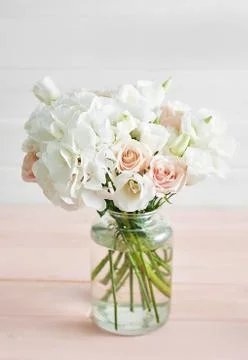 Bouquet of roses, eustomas and hydrangeas on table. Cup of tea and photo fram Stock Photos
