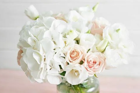 Bouquet of roses, eustomas and hydrangeas on table. Cup of tea and photo fram Foto stock