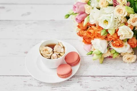 Bouquet of roses, eustomas and hydrangeas on table. Cup of tea or coffee and  Stock Photos