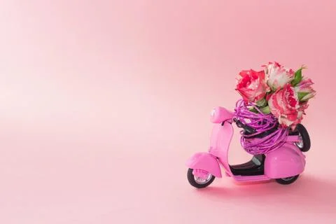 Bouquet of roses flower in basket on backseat of cute pink scooter on pink ba Stock Photos