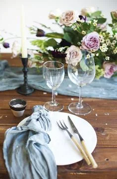 Bouquets of pink flowers on a table set for dinner with candles, close up Foto stock