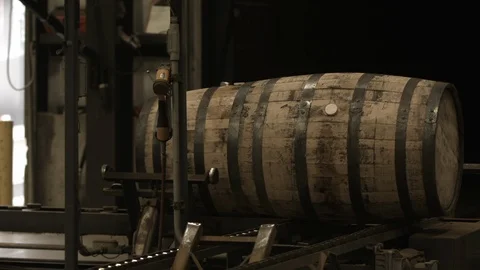 Bourbon barrels moving down a conveyor belt inside of a factory. Stock Footage 101521812