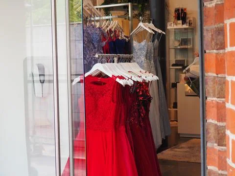 Boutique store window display with an array of vibrant red dresses suspended fro 스톡 사진
