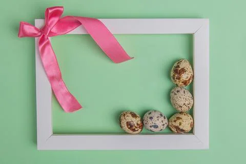 Bow and quail eggs in a frame on a green background Stock Photos