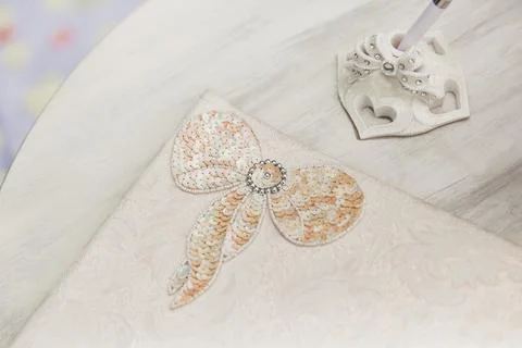 Bow of beige sequins and white beads, embroidered on a napkin for table setti Stock Photos