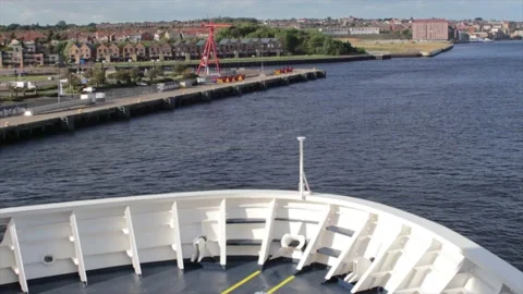 Bow of large ship moving down river past industrial and residential areas Stock Footage 169086497