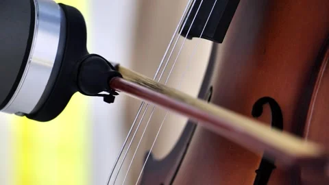 Bow moving across cello strings creating classical music sound Stock Footage 321349141