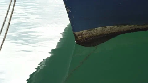 Bow of an old boat with peeling paint that floats on water on pier, swimming on Stock Footage 197468942